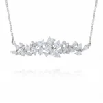 Diamond necklace with clusters of square, marquise, and baguette-cut stones set in white metal chain, centered sparkle against white background.