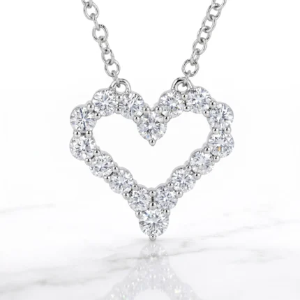 Heart-shaped diamond pendant necklace on a silver chain, with round-cut stones forming the outline against a white background.