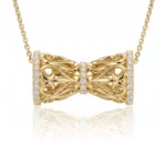 Gold bow-shaped pendant necklace with diamond accents along the edges, hanging from a delicate gold chain.