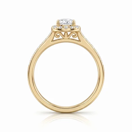 Gold engagement ring with a cushion-cut center diamond and pavé diamonds along the band, featuring delicate scrollwork beneath the setting.