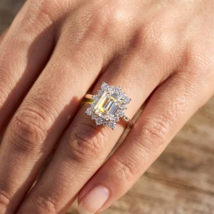 Close-up of a hand wearing a white-gold ring with a large emerald-cut diamond surrounded by a halo of small diamonds
