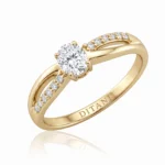 Gold ring with a solitaire round diamond and pavé diamonds along the shoulders.