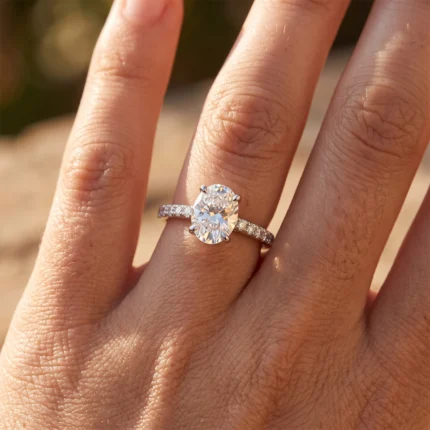Close-up of an oval-cut diamond engagement ring on a finger with a pavé band.