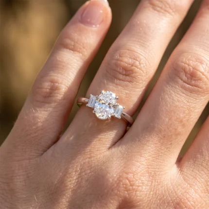 Engagement ring on finger featuring a large oval diamond with two side baguette stones on a slim band in sunlight] }}`}Oops format must be proper JSON array. Let's provide multiple strings. Remove extra braces. Provide proper. Let's craft: {