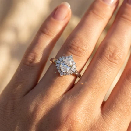 Close-up of a diamond engagement ring on a finger, featuring a central oval diamond with a halo of smaller diamonds and baguette-cut stones, rose-gold band.