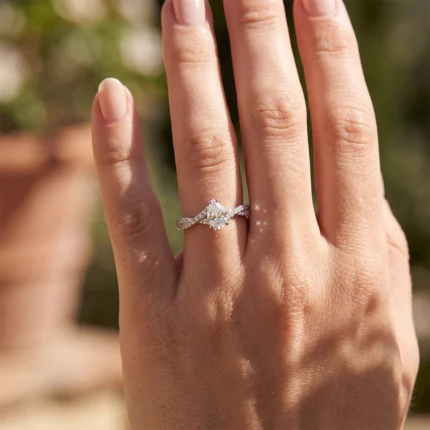 Close-up of a hand wearing a sparkling diamond engagement ring on the ring finger outdoors in sunlight, showing a large center stone and pavé band.