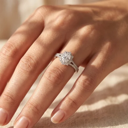 Close-up of a diamond halo engagement ring on a woman's finger, sparkling in warm light.