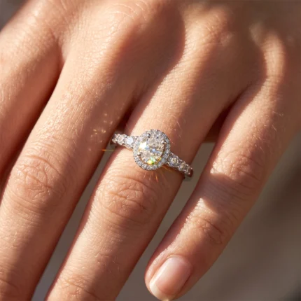 Close-up of a hand wearing a halo engagement ring with a pear-shaped center diamond and pavé diamonds along the band.