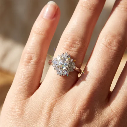 Close-up of a diamond cluster ring on a finger, with a square-cut center stone surrounded by baguette and pavé diamonds.