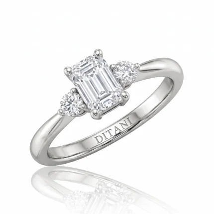Diamond ring with an emerald-cut center stone and two round side diamonds on a polished silver band.