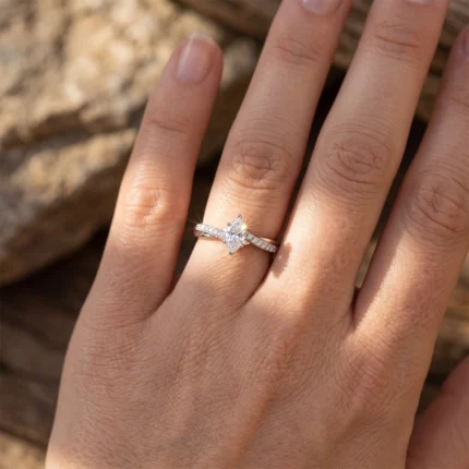 Close-up of a hand showing an engagement ring with a square-cut diamond and pavé band on the ring finger.