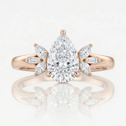 Rose gold engagement ring with a pear-shaped center diamond and marquise/baguette diamond accents on the sides.