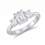 Silver ring with three emerald-cut diamonds, center largest, prong-set on a polished band; engraving inside reads 'DITANI'.