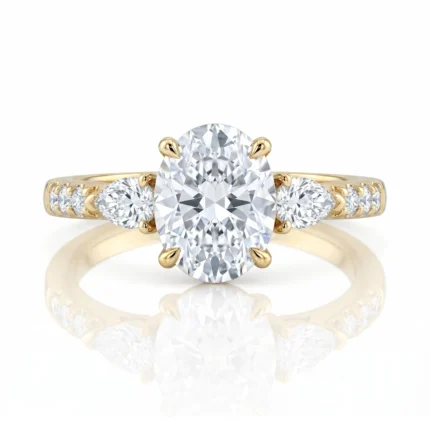 Gold engagement ring featuring a large oval-cut center diamond with two pear-shaped side diamonds and a pavé-set band on either side