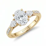 Gold ring with a large round center diamond and two pear-cut side diamonds, engraved 'DITANI' on the band, ornate setting.